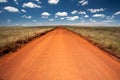 Rural orange dirt road with blue sky and far horizon Royalty Free Stock Photo