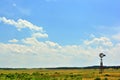 Rural Ranch Prairie Field with an Antique Windmill and Puffy White Clouds Royalty Free Stock Photo