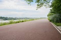 Rural red-painted way along river in cloudy summer afternoon Royalty Free Stock Photo