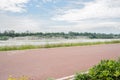 Rural red-painted way along river in cloudy summer afternoon Royalty Free Stock Photo