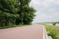 Rural red-painted way on flowering riverbank in cloudy summer afternoon Royalty Free Stock Photo