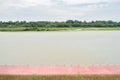 Rural riverside red-painted path in cloudy summer afternoon Royalty Free Stock Photo