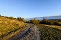 Rural road in autumn landscape. Mountain rural road with water a Royalty Free Stock Photo