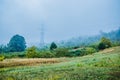 Rural road in a foggy morning on a big mountain. Foggy summer morning in the mountains and a small village. Country road in the Royalty Free Stock Photo