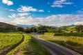 Rural Road Among Grean Fields. Amazing Blue Sky With Beautiful Clouds, Mountains, Meadow With Fresh Green Grass. Highway In Rio. Royalty Free Stock Photo