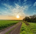 Rural road in green field and orange sunset Royalty Free Stock Photo