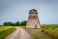 Rural road leading through the fields to the abandoned windmill. Royalty Free Stock Photo