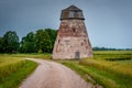 Rural road leading through the fields to the abandoned windmill. Royalty Free Stock Photo