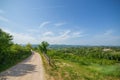 Rural road passing a village surrounded with forest, sunny day s Royalty Free Stock Photo