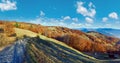 Rural road, shadows of trees and autumn trees on mountain slope Royalty Free Stock Photo