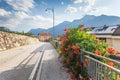 Rural road in suburb of Trento, Alps on background, solar panels on a roof, flowers of Chinese trumpet vine