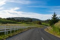 Rural road surrounded by a white picket fence and lush green grass. Royalty Free Stock Photo