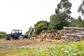 Rural scene with stacked trees and a tractor with wood splitter to chop firewood Royalty Free Stock Photo