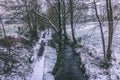 Stream surrounded by trees and roads covered in snow during storm Emma. Royalty Free Stock Photo