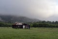 rural simple house in the forest in the morning at the foot of the mountain in a thick fog, gloomy disturbing landscape Royalty Free Stock Photo