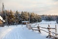 Rural snowy covered road with wooden fence along is in Russian village in winter season. Russia Royalty Free Stock Photo