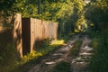 Rural spring landscape with a road going into the distance and a fence on the left side. Soft evening, sunlight floods Royalty Free Stock Photo