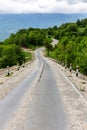 Rural tarmac winding downhill road covered with loose stones and gravel from Khvamli mountain