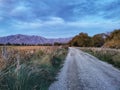 A rural unsealed road with cloudy sky and mountains on the background Royalty Free Stock Photo