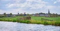 Panoramic scenery of Hazerswoude-dorp amidst green meadows with wooden fence in the foreground