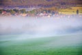 Rural village in calm spring morning covered in mist