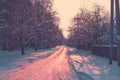 Country road covered with snow between houses and woods Royalty Free Stock Photo