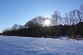 Rural winter landscape with a field snow and the blue sky. Low winter sun Royalty Free Stock Photo