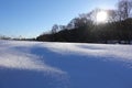 Rural winter landscape with a field snow and the blue sky. Low winter sun Royalty Free Stock Photo