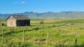 Rural wooden house with metallic fence next to it in the middle of a green field Royalty Free Stock Photo