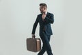 Rushed businessman with baggage fixing tie and looking over shoulder