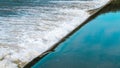 Rushing river weir water flowing over a dam reservoir ledge with blue sky reflections Royalty Free Stock Photo