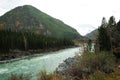 A rushing stream of a beautiful turquoise river flowing through an autumnal valley at the foot of a high mountain Royalty Free Stock Photo