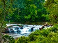 Rushing waterfall spilling over rocks into a stream during summer Royalty Free Stock Photo