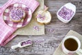 Flat lay with rusk, sweet pink purple sprinkles and cup of tea. Against wooden background