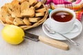 Rusks with raisin in wicker basket, tea, lemon, knife