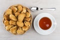 Rusks with raisin in wicker basket, tea and teaspoon