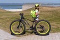 Russia, Bolgar - June 09, 2019 Kol Gali Resort Spa: Child girl with a bicycle GTX with a backpack in her hands stands on the shore