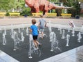 Russia, Boronezh region - august,2020: Toddler playing with small fountains on the urban plaza