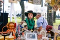 Russia, city Moscow - September 6, 2014: Young beautiful girl in a hat with paly and green scarf. A woman sells antiques in a