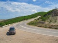 A Volkswagen minibus is parked on a mountain serpentine