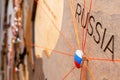 Russia flag on the pushpin and red threads on the wooden map