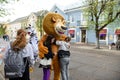 A man in a lion costume on a city street embraces and takes photos with passers-by. Advertising on the street. Work in advertising