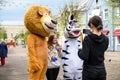 A man in a lion and zebra costume on a city street embraces and takes photos with passers-by. Advertising on the street. Work in