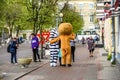 A mans in a lion and zebra costume on a city street embraces and takes photos with passers-by. Advertising on the street. Work in