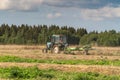 Russia. Gatchinsky district of the Leningrad region. August 28, 2021. The tractor puts hay on the field in the tracks Royalty Free Stock Photo