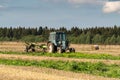 Russia. Gatchinsky district of the Leningrad region. August 28, 2021. The tractor puts hay on the field in the tracks Royalty Free Stock Photo