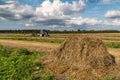 Russia. Gatchinsky district of the Leningrad region. August 28, 2021. The tractor puts hay on the field in the tracks Royalty Free Stock Photo