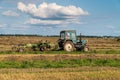 Russia. Gatchinsky district of the Leningrad region. August 28, 2021. The tractor puts hay on the field in the tracks Royalty Free Stock Photo