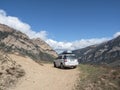 White Rover car suv at the crossroads of mountain dirt roads. Luggage trunk box mountain on car roof rack