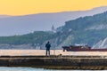 Russia, Kabardinka, May 02, 2019: Beautiful sunset view. Fisherman on concrete pier